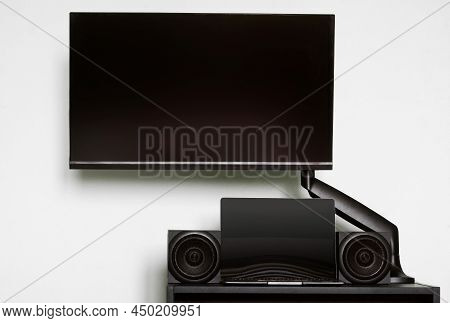Modern Computer Monitor Is Mounted On A Small Table, Along With Audio Speakers And A Laptop, Using A