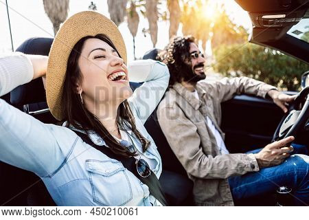 Happy Young Couple Laughing Together While Driving A Convertible Car On Holidays - Two Millennial Pe