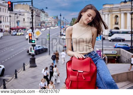 Woman Holds Red Leatherette Backpack Bag On Crowded City Street.