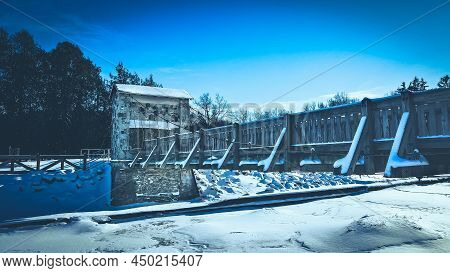 A Snow Covered Hiking Trail Bridge Over A Frozen River In Winter At A Local Park