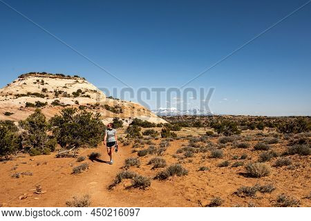 Hiker Walking Along Tail To The Aztec Buttes In Canyonlands National Park