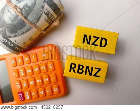 Top View Calculator And Banknotes With Text Nzd Rbnz On White Background.