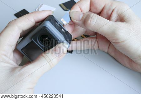Action Camera And Microsd Memory Card In Hands On The Back Of Other Sd Memory Cards. Background From