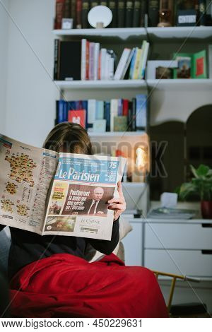 Paris, France - Feb 23, 2022: Woman Reading French Newspaper Le Parisien With Headlines Russian Pres