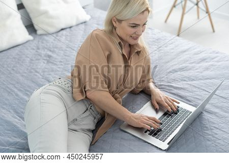 Nice Beautiful Blonde Lady Works At The Notebook Sit Down On The Sofa At Home - Check On Oline Shops