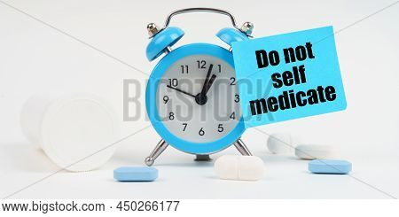 Medical Concept. On A White Surface There Are Pills And An Alarm Clock, On Which There Is A Sticker 