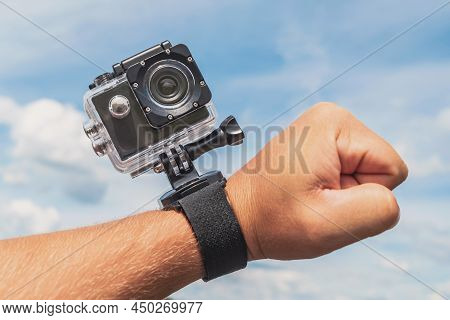 Close-up, Action Camera On A Man's Hand. Against The Background Of A Blue Sky With Clouds.