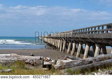 Tolaga Bay New Zealand - February 5 2022: Historic Long Wharf Structure Stretching Into Bay With Sma