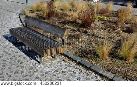 Perennial Bed Mulched With Gray Gravel In Front Of A Limestone Stone Wall In A Square With Benches W