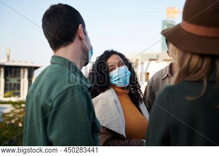 Multi-culural Female And Diverse Group Of Friends Chatting On A Rooftop Terrace With Masks On. City 