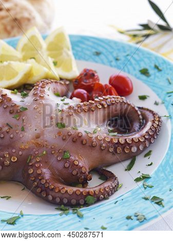 Semi Sun Dried And Boiled Octopus,served In A Plate,with Lemon,olive Oil And Fresh Herbs