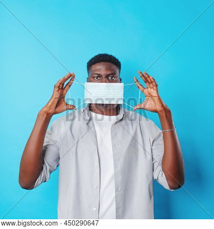 An African-american Man Wears A Medical Mask On A Blue Isolated Background