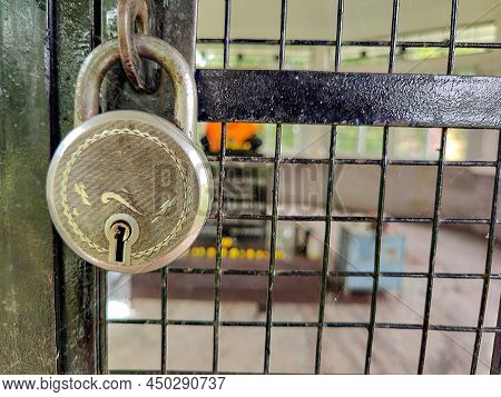 Stock Photo Of Closed Black Color Painted Sliding Grill Gate With Hanging Silver Padlock On Blur Bac