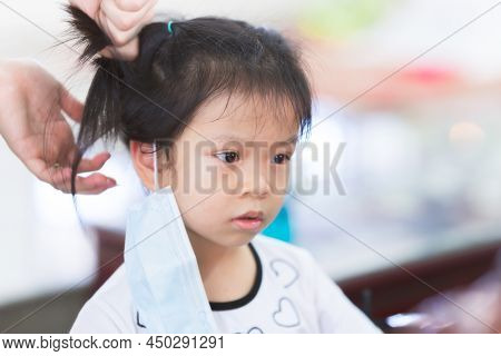 Portrait Cute Kid Girl Sits Still And Let Grown-ups Do Her Hair. Child Take Off Face Mask. 4 Year Ol