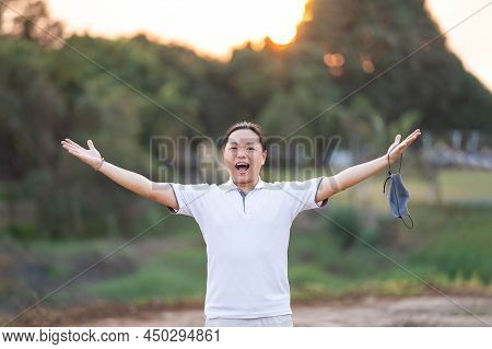 Asian Man Take Off Mask And Rise His Hand Up In Golden Twilight Time.