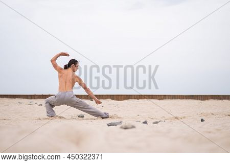Caucasian Man With Long Hair Practicing Qigong Outdoors.