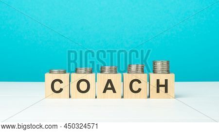 Wooden Blocks With Text Coach And Coins On Wooden Table. Copy Space. Blue Background