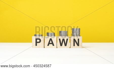 Wooden Cube On A Concrete Surface With Text Pawn. Copy Space On Right For Design, Yellow Background