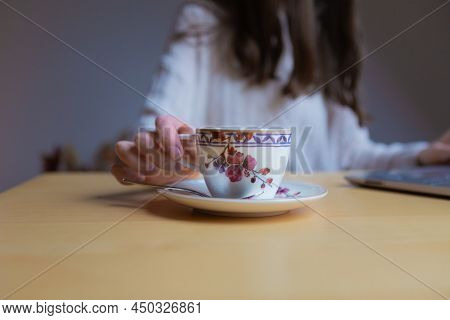 A Woman\'s Hand Holding A Cup Whilst Working