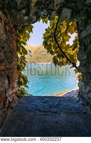 Nesso, Italy - May 2021: View Of Lake Como By A Couple On A Surfboard From A Crevice Covered With Ve