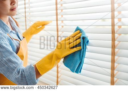 Young Asian Woman Cleaning House Wiping Dust Using Feather Broom And Duster While Cleaning On Window