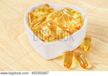 Cod Liver Oil Capsules In White Cup On Wooden Flloor.
