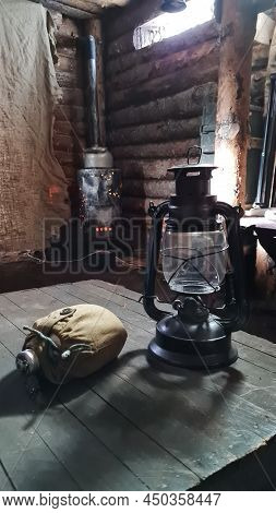 A Wooden Dugout In Which A Kerosene Lamp Burns. Light From The Window Penetrates Into The Room.