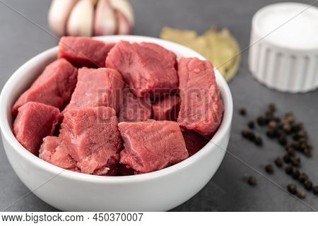 Chopped Topside Meat In A Bowl With Seasonings Over Stone Background.