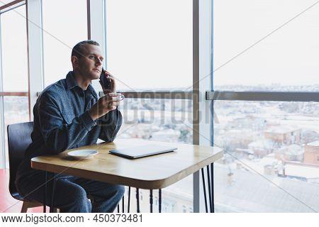 Happy Man With Coffee Calling Via Smartphone While Remote Working Laptop At Work Desk, Cheerful Free
