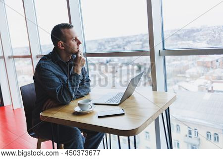 A Young Successful Businessman In A Suit Drinks Coffee And Works In A Cafe On Wireless Free Internet