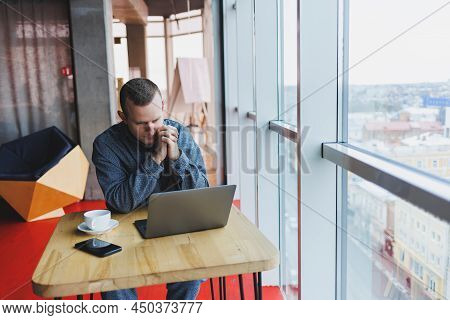 A Young Successful Businessman In A Suit Drinks Coffee And Works In A Cafe On Wireless Free Internet
