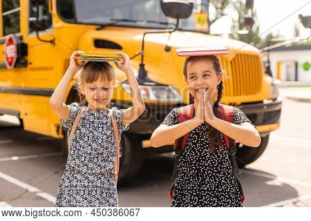 Cheerful Little Girls Next To School Bus. Backback. Back To School Concept.