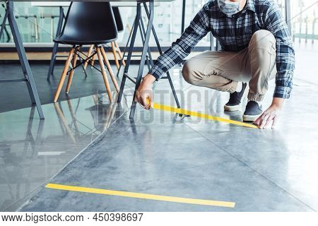 Business Man Tape Being Attached Behind Social Distancing Signage On Office Floor During Covid-19 Pa