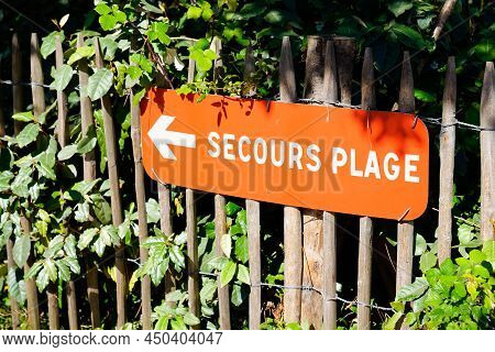 Arrow Road Sign Indicates The Lifeguard Station On The Beach In French Text Means Secours Plage