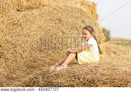 Portrait Of Happy Little Girl With Eyes Squinted From Sun And Long Braid On Head Looking Away Sittin