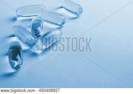 Fish Oil Softgels. Vitamins And Healthy Lifestyle. Blue Tinted Background Or Backdrop With Copy Spac