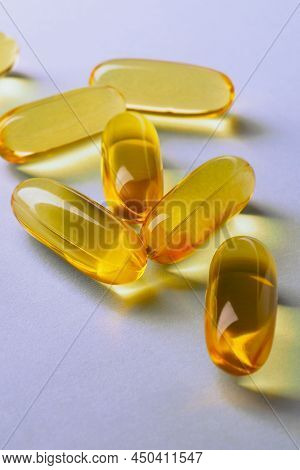 Fish Oil. Yellow Softgels Or Capsules Lie On Violet Surface. Vertical Illustration About Vitamins An