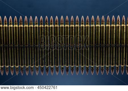 Line Of 5.56 Rounds On Dark Reflective Surface
