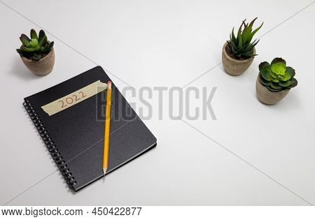 Spiral Notebook On White Desk With Small Plants