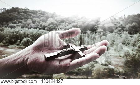 Hand Holding Holy Cross With Bright Shining Light.