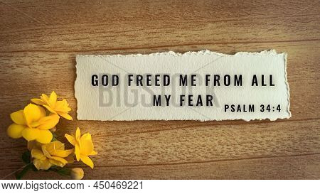 Top View Of Bible Verse God Freed Me From All My Fear. Yellow Flower And Wooden Background.