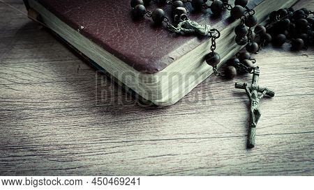 Holy Bible And Holy Rosary On Wooden Desk.