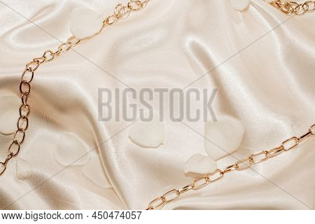 Golden Chain And White Petals On A Silk Beige Background, Space For Text.