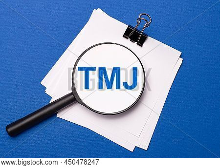 On A Blue Background, White Sheets Under A Black Paper Clip And On Them A Magnifying Glass With The 