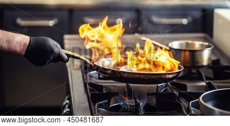 Pro Chef Flambeing In The Kitchen In A Pan On A Gas-fired Stove.
