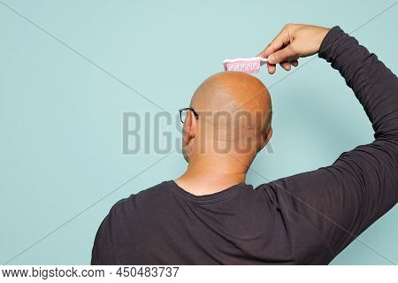 Bald Man Combs The Back Of His Head With A Baby Comb On A Turquoise Background. Funny Look At The Pr