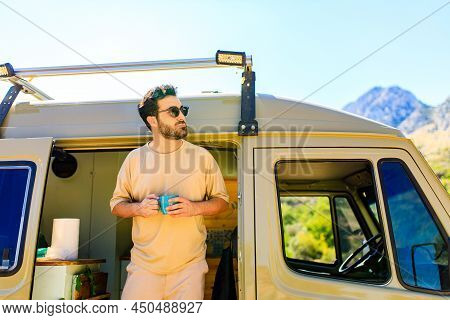 Man In Charming Trailer House Makes Coffee Outdoors In Mountains In Summer Sunny Day