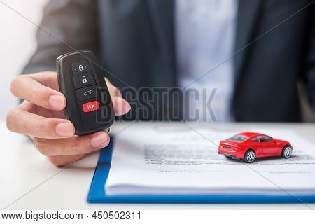 Businessman Hand Holding Remote Keyless With Car Toy, Pen And Contract Document. Buy And Sale, Insur