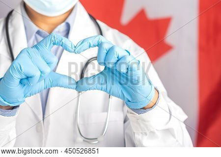Happy Doctor Wearing Gloves Hands Showing Heart Shape Against The Canada Flag Background. Medical He