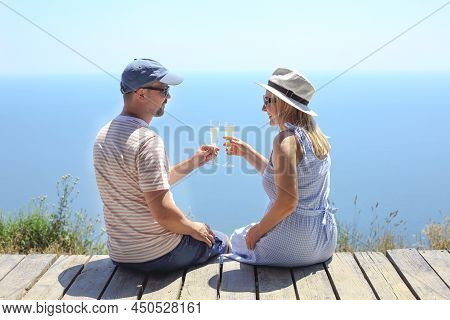 Two Glasses Of Champagne In The Hands Of A Man And A Woman. Romantic Trip Concept